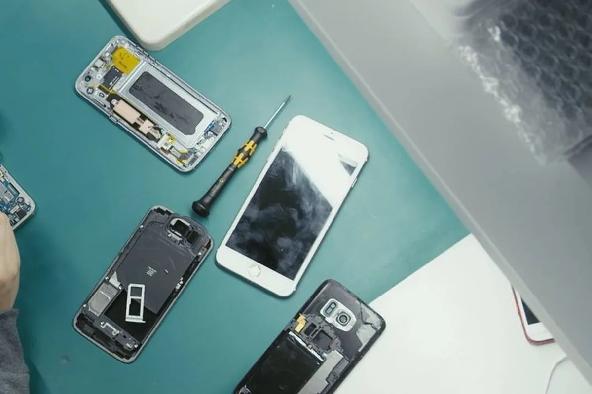 Overhead view of a repair bench with opened smartphones and precision tools